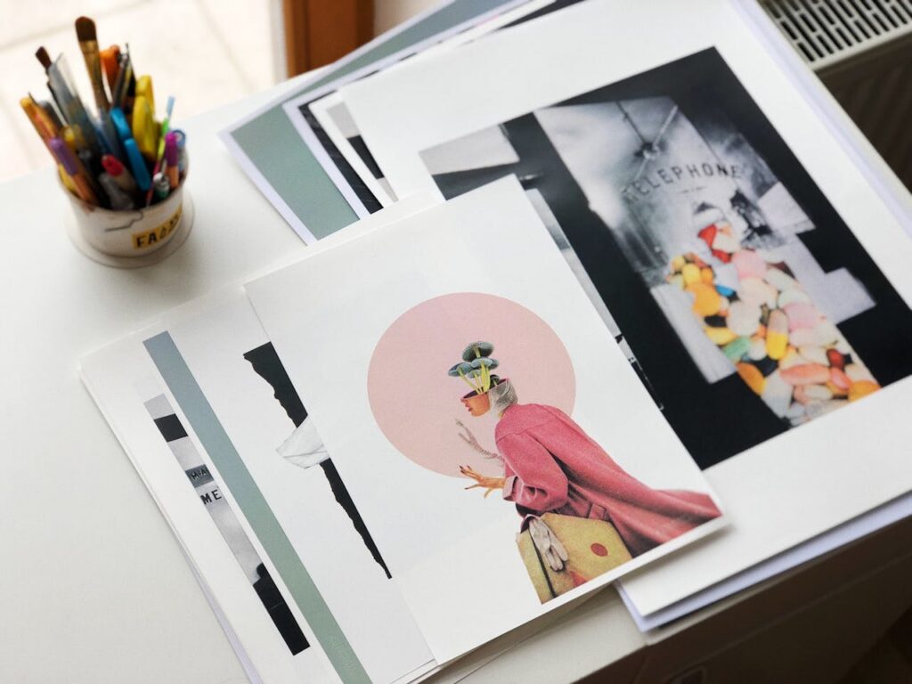 Artistic collage creations on a desk alongside vibrant stationery items.